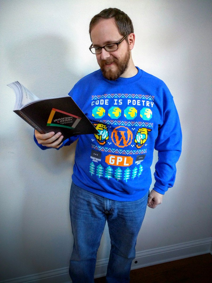 Picture of me wearing a WP "ugly sweater" style sweatshirt while holding a programming book.