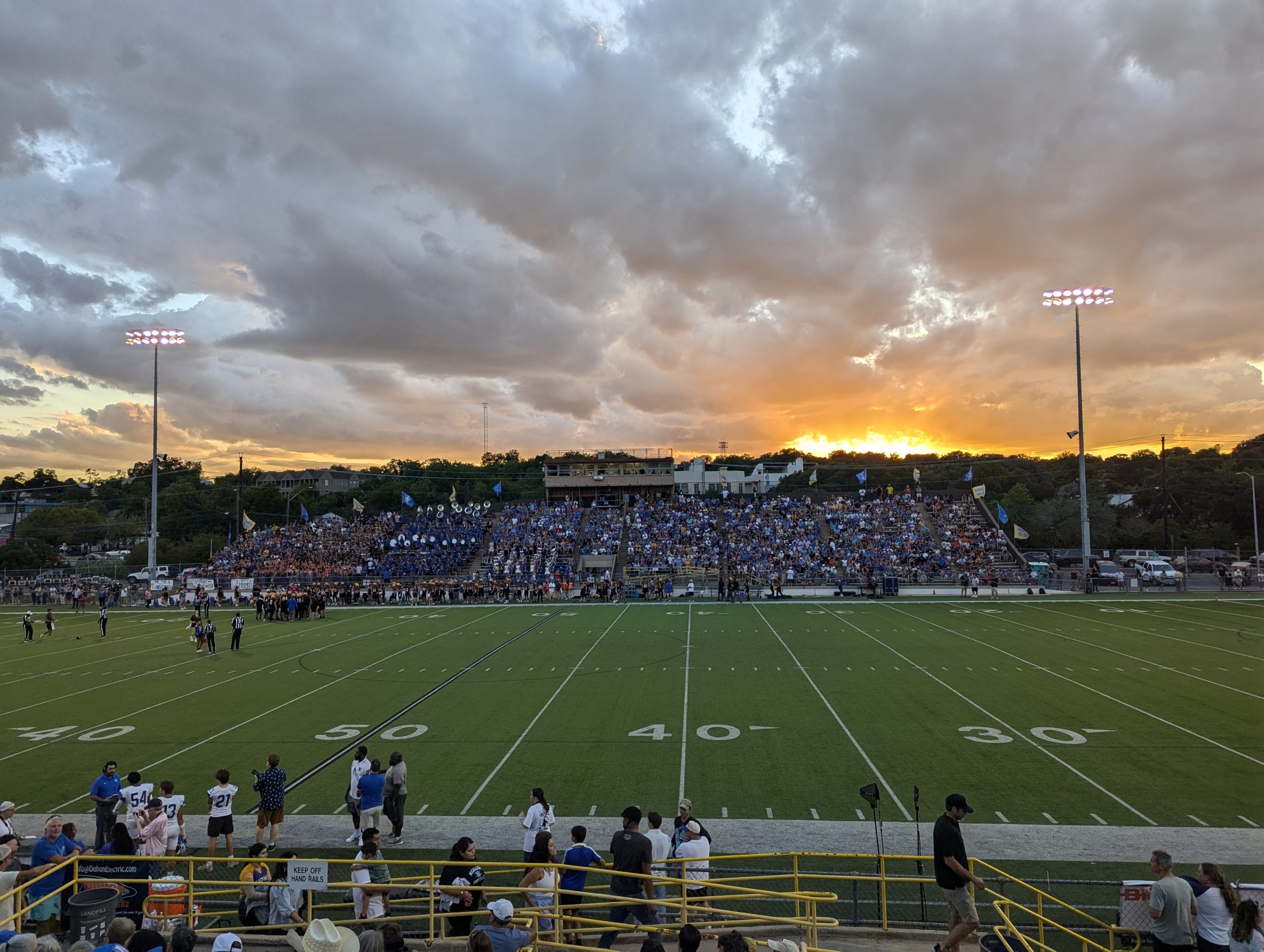 Picture of a football stadium at dusk with the sun setting behind the stands.