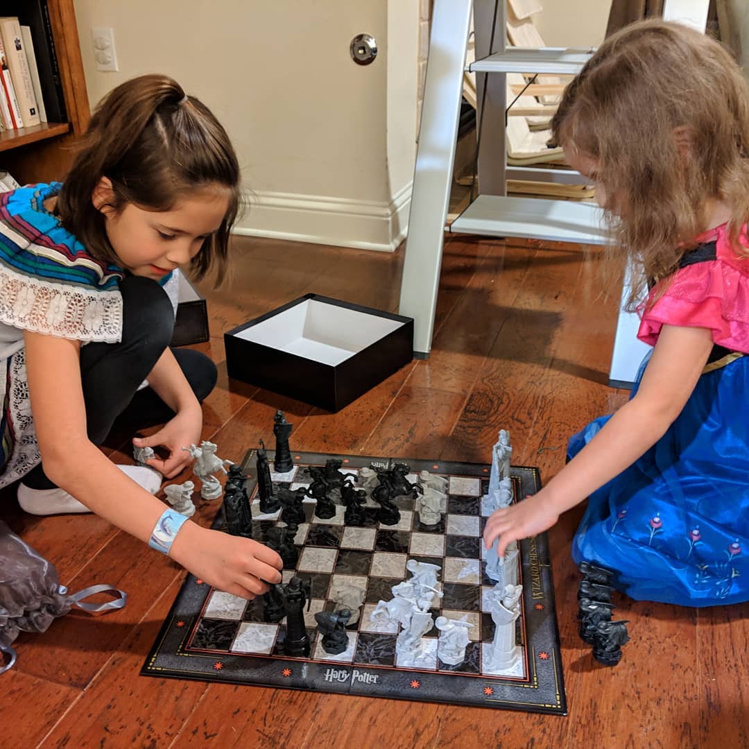 Catalina teaching Ana (while she’s wearing her Frozen Princess Anna’s pajamas) how to play chess on a Harry Potter board